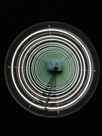 A series of concentric circles of light create a tunnel-like illusion in a dark environment. The circular lights appear to decrease in size, creating a sense of depth and infinity.