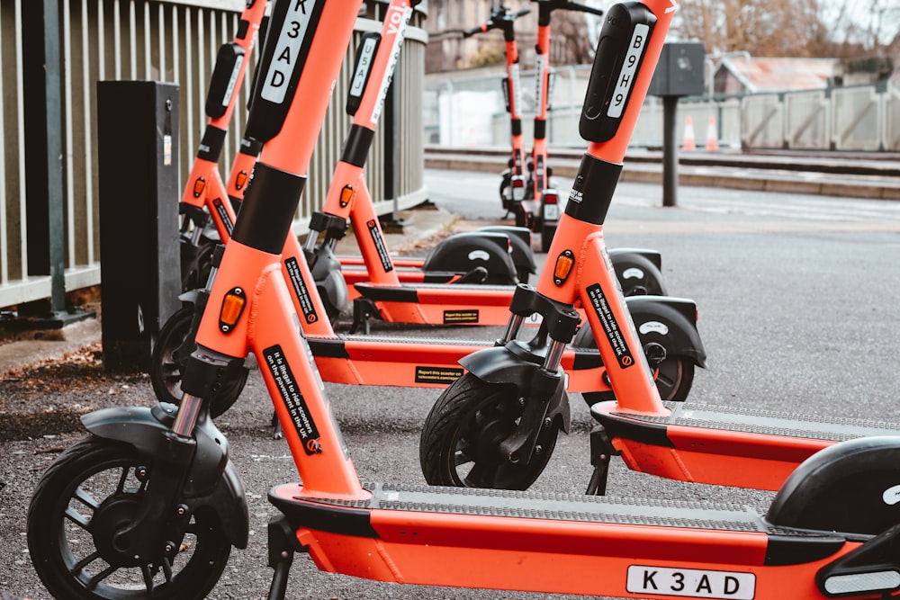 Un grupo de scooters naranjas estacionados uno al lado del otro