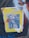 A poster is pasted on a surface with graffiti. The poster has a yellow background with black and white images in the center, depicting a scene involving law enforcement officers and a person being restrained. One part of the text reads 'CARABINEROS DE CHILE', and there is large text at the top saying 'SIN MIEDO'. Red and black graphic elements, including zigzag lines, overlay the image.