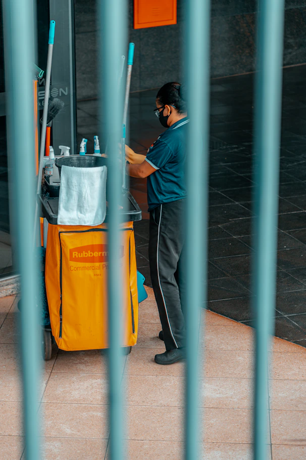 woman in blue t-shirt and blue denim jeans standing beside blue metal pole