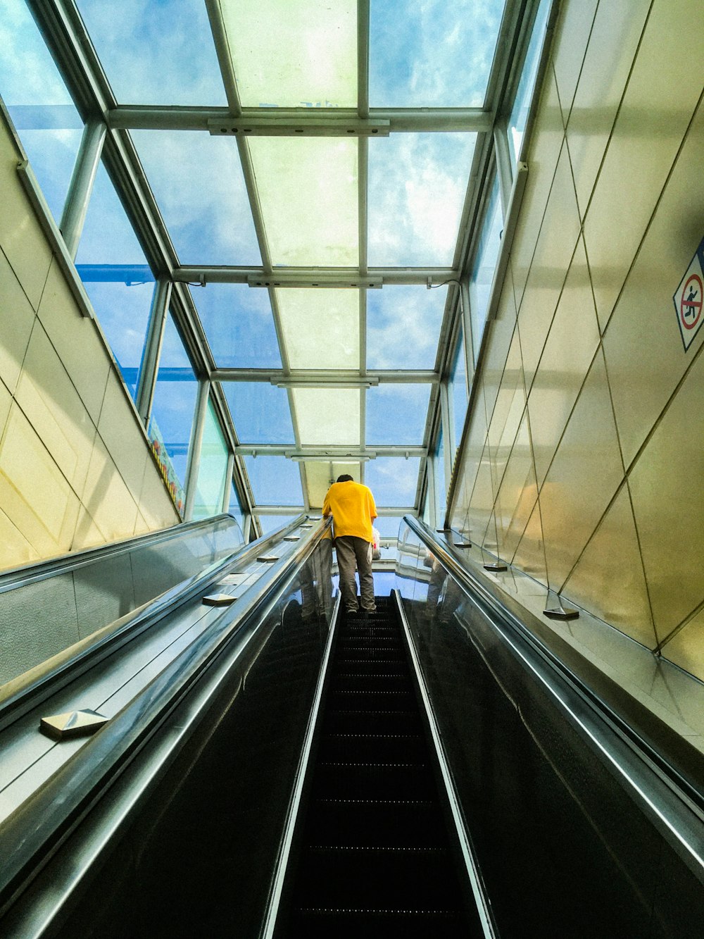 person in yellow jacket walking on escalator