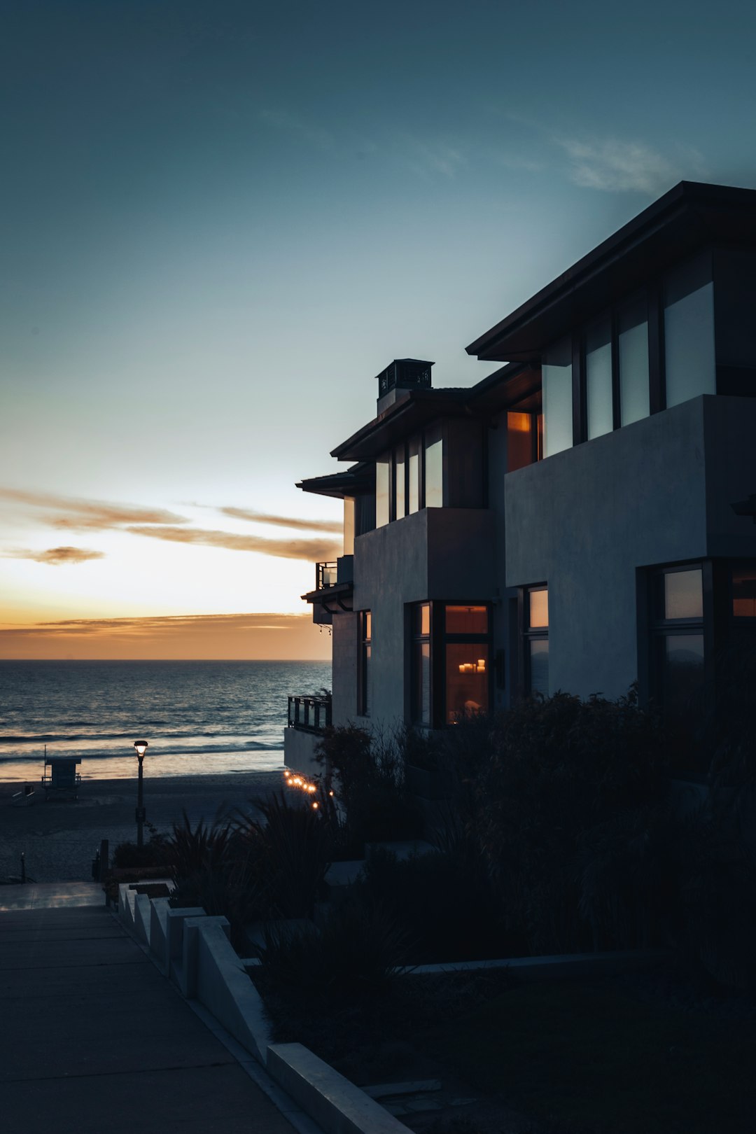 silhouette of house near body of water during sunset