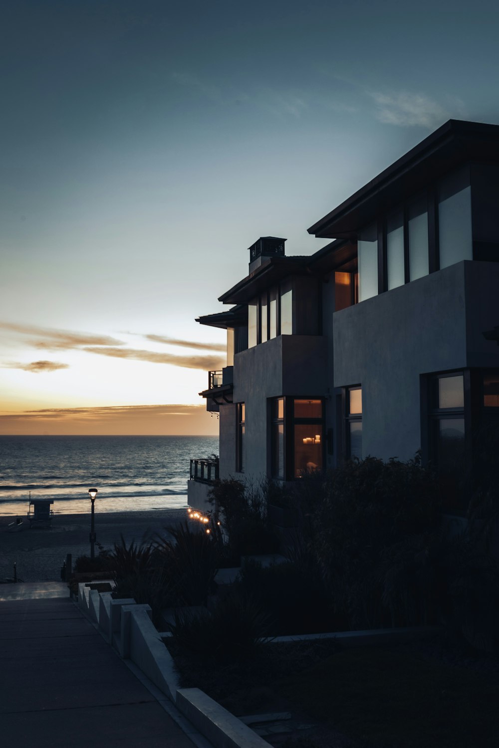 silhouette of house near body of water during sunset