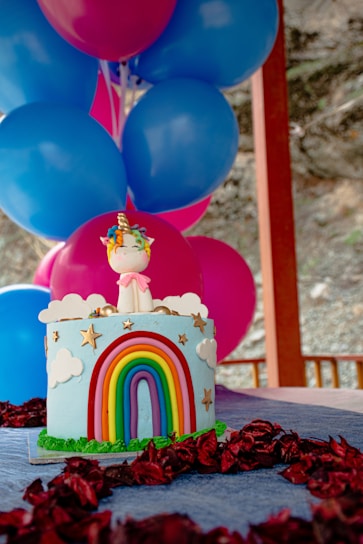 Colorful birthday piñata shaped like a smiling unicorn surrounded by confetti and balloons