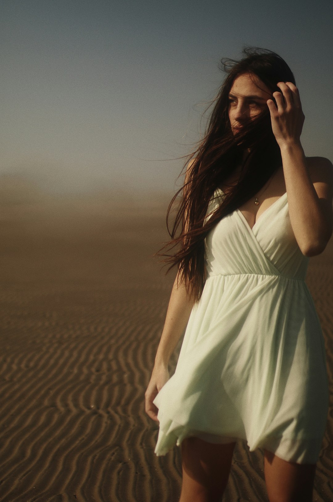 woman in white dress standing on sand during daytime