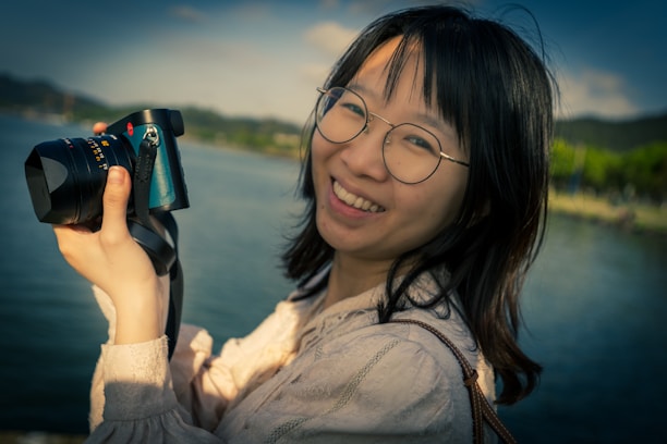 Happy customer holding a sleek camera outdoors with a bright smile.