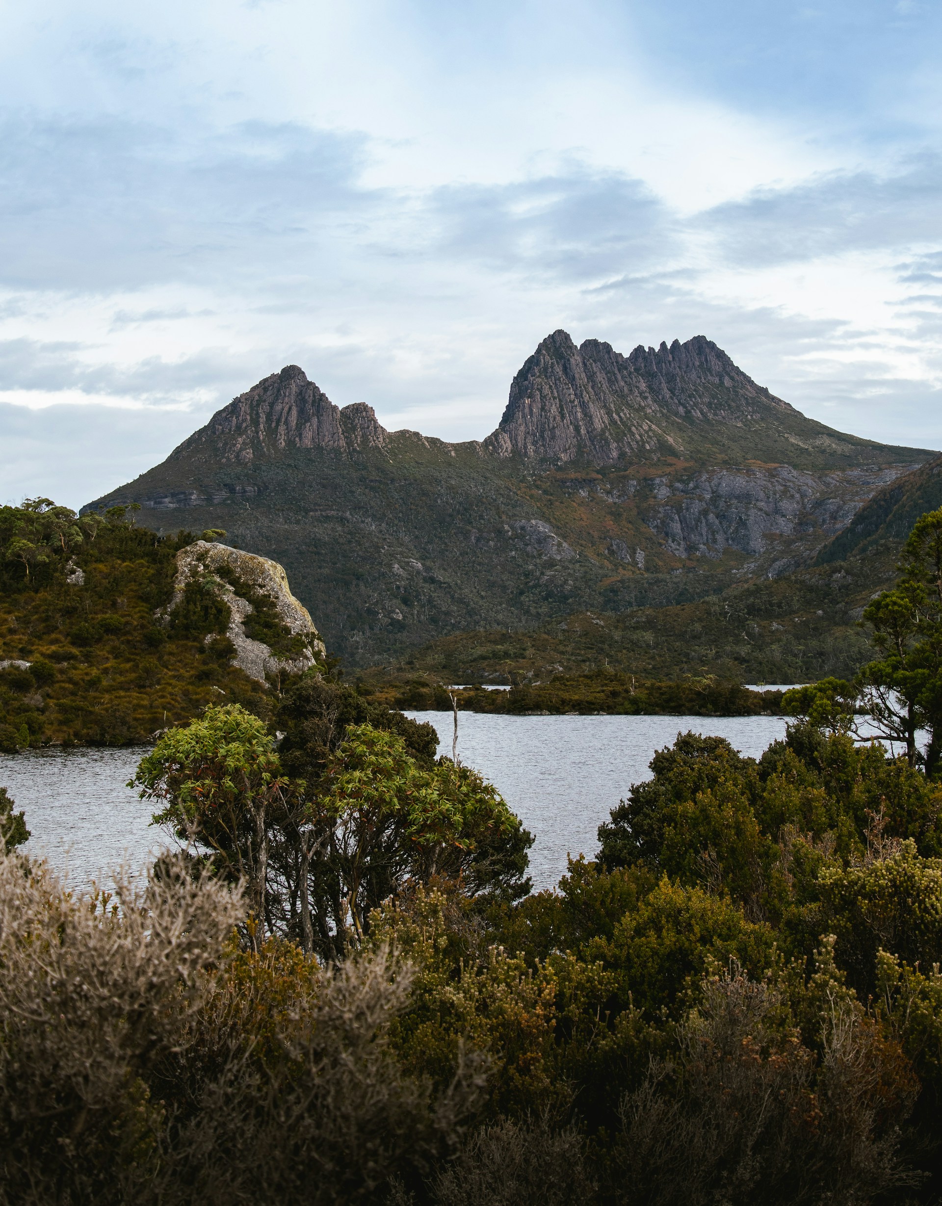 A serene landscape featuring a calm lake surrounded by lush greenery and distant mountains.