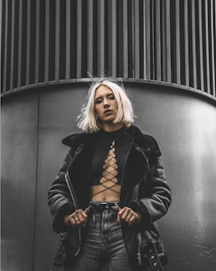 woman in black leather jacket standing beside black wall