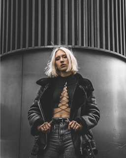 woman in black leather jacket standing beside black wall