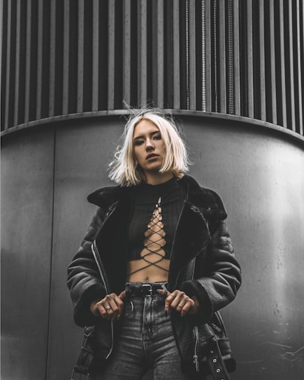 woman in black leather jacket standing beside black wall