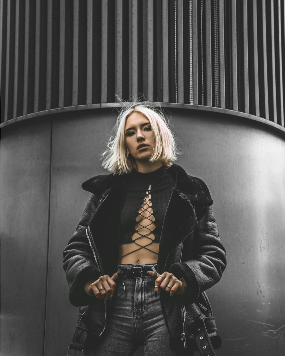 woman in black leather jacket standing beside black wall