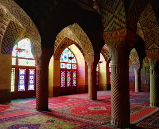 A close-up of a beautifully detailed mosque carpet with intricate patterns in deep reds and golds.