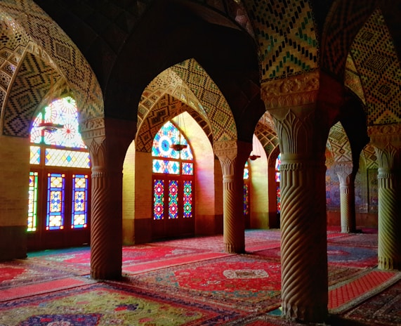 The mosque's beautifully patterned prayer area with sunlight coming through stained glass.