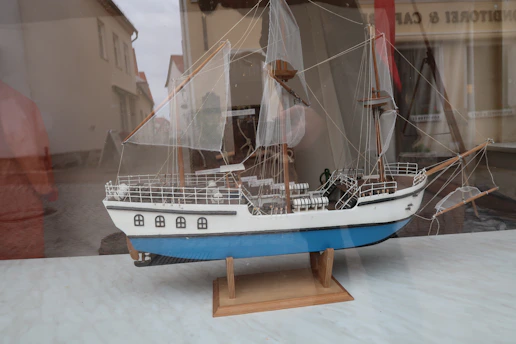 Close-up of a sleek 3D-printed RC sailing yacht model on a minimalist wooden table.