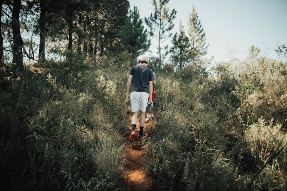 man in gray t-shirt walking on brown dirt road during daytime