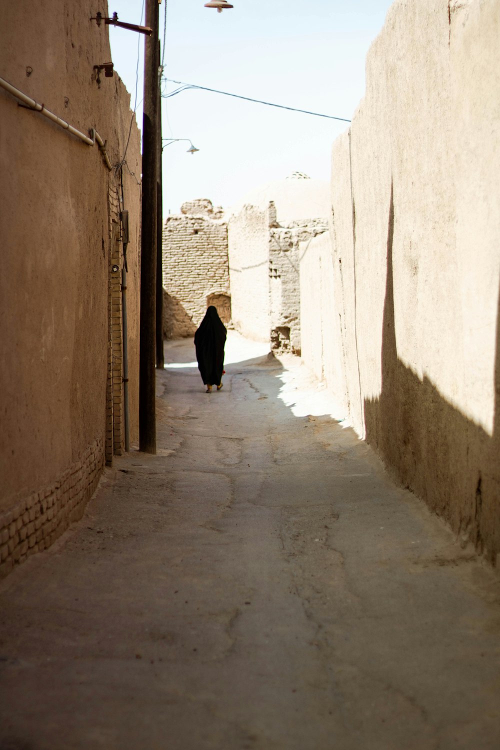 femme en robe noire marchant dans la rue pendant la journée