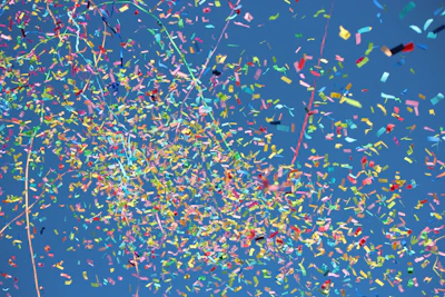 Close-up of colorful powder exploding in the air against a bright blue sky.