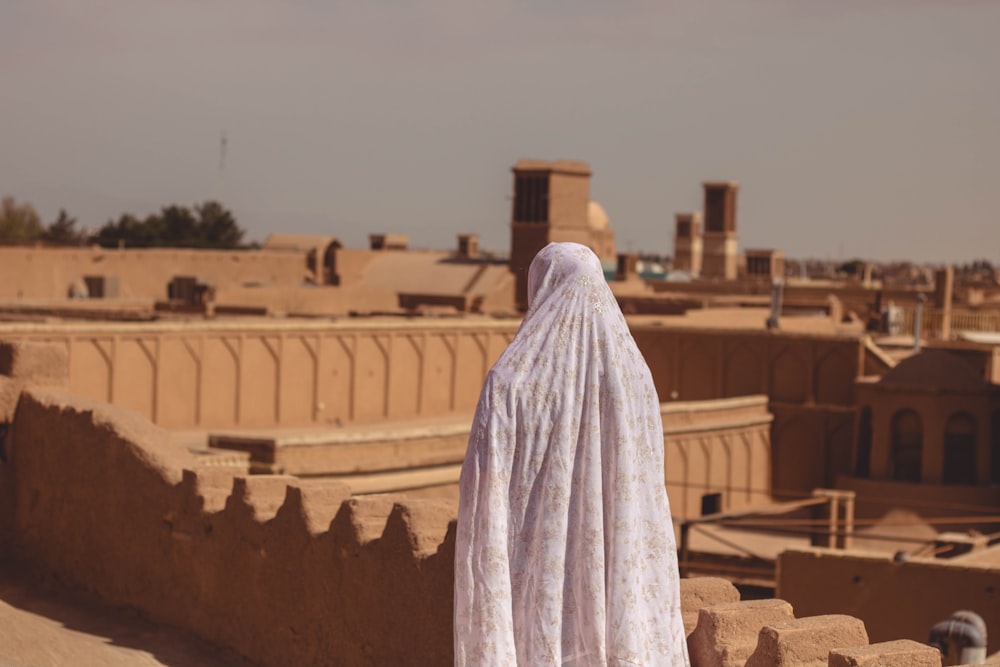 person in white robe standing on brown concrete stairs during daytime