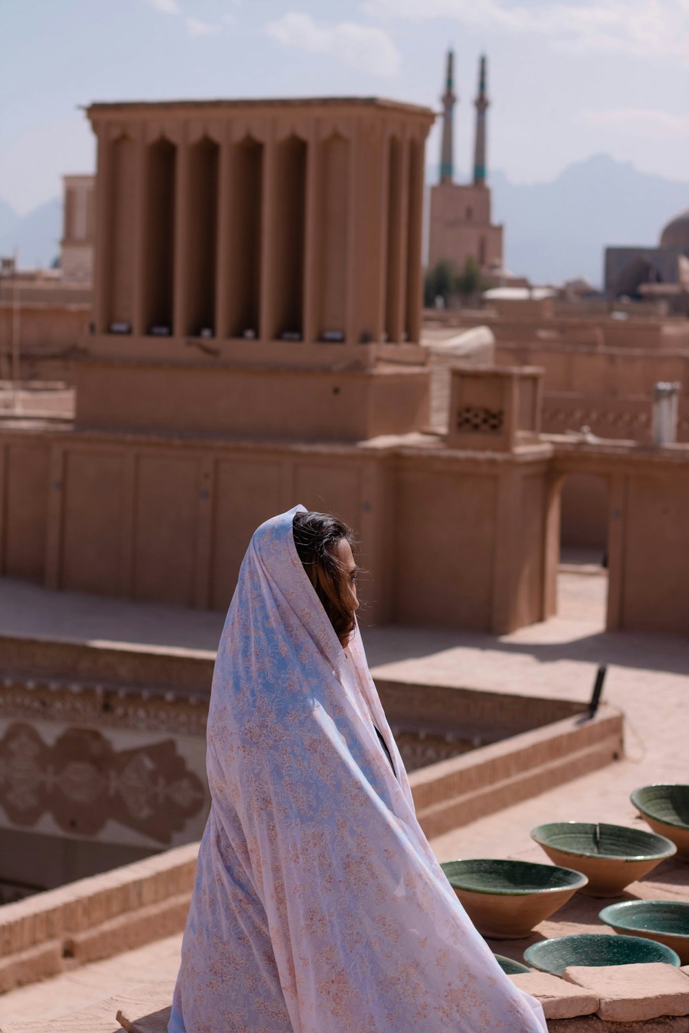 woman in white hijab sitting on brown concrete bench during daytime