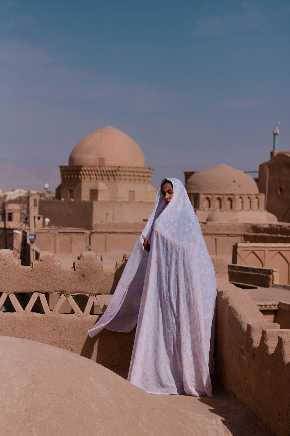 Persona con hijab blanco de pie sobre arena marrón durante el día