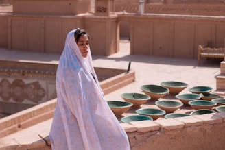 woman in white hijab standing near green round plastic basin