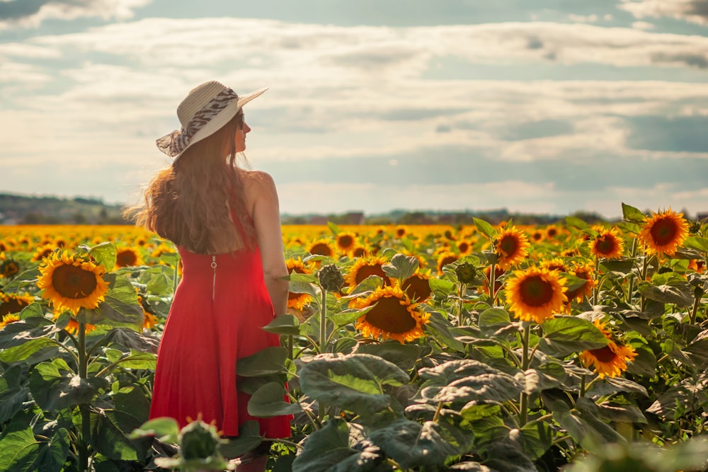 woman in red dress standing on sunflower field during daytime