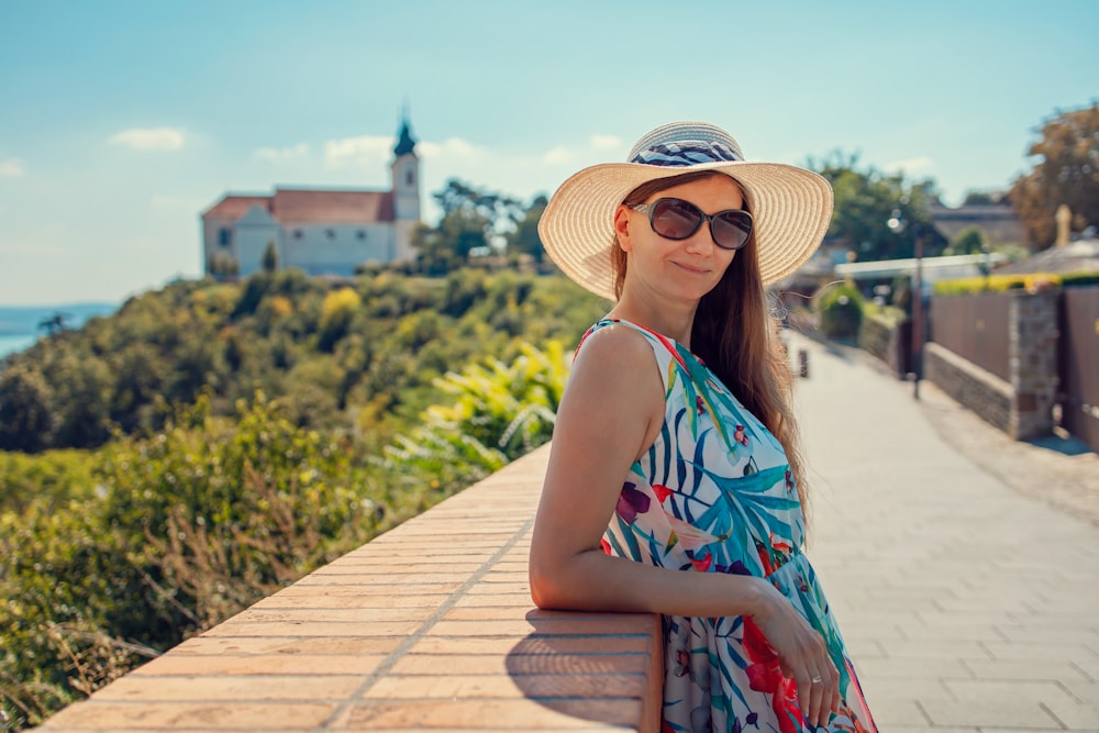 woman in blue and white floral halter top sitting on brown wooden dock during daytime