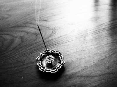 Elegant incense burner shaped like a lotus flower with curling smoke trails.