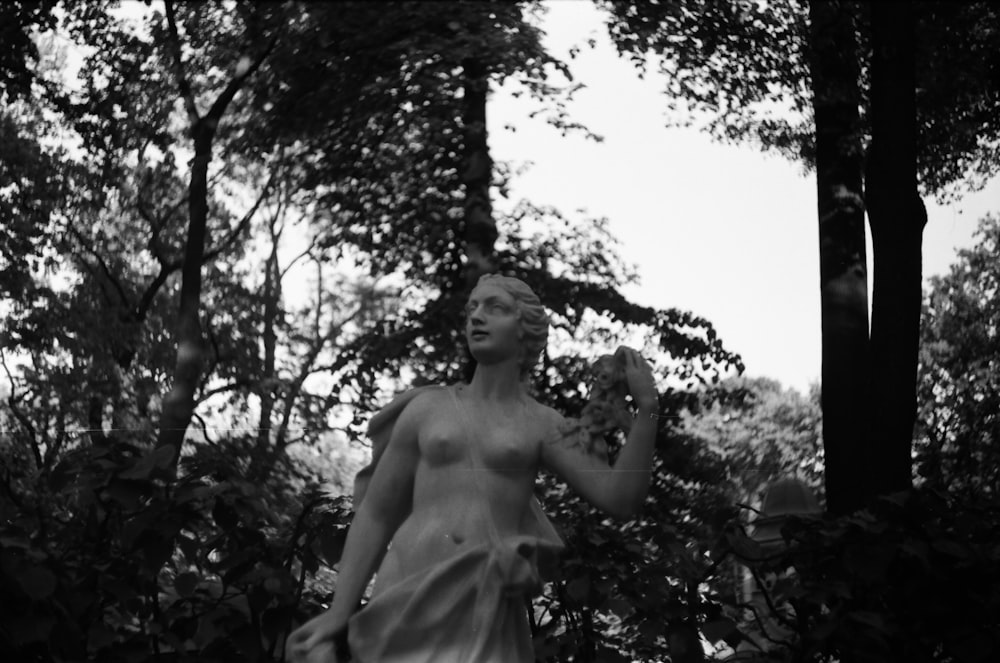 grayscale photo of topless woman standing near tree