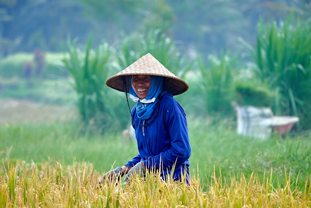 Mujer con chaqueta azul con sombrero marrón de pie en el campo de hierba verde durante el día