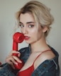 woman in red and black tank top holding red telephone
