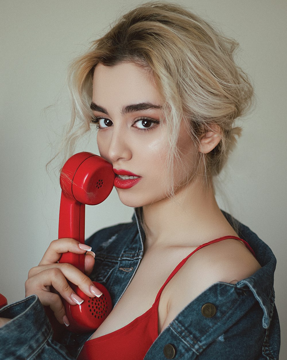 woman in red and black tank top holding red telephone