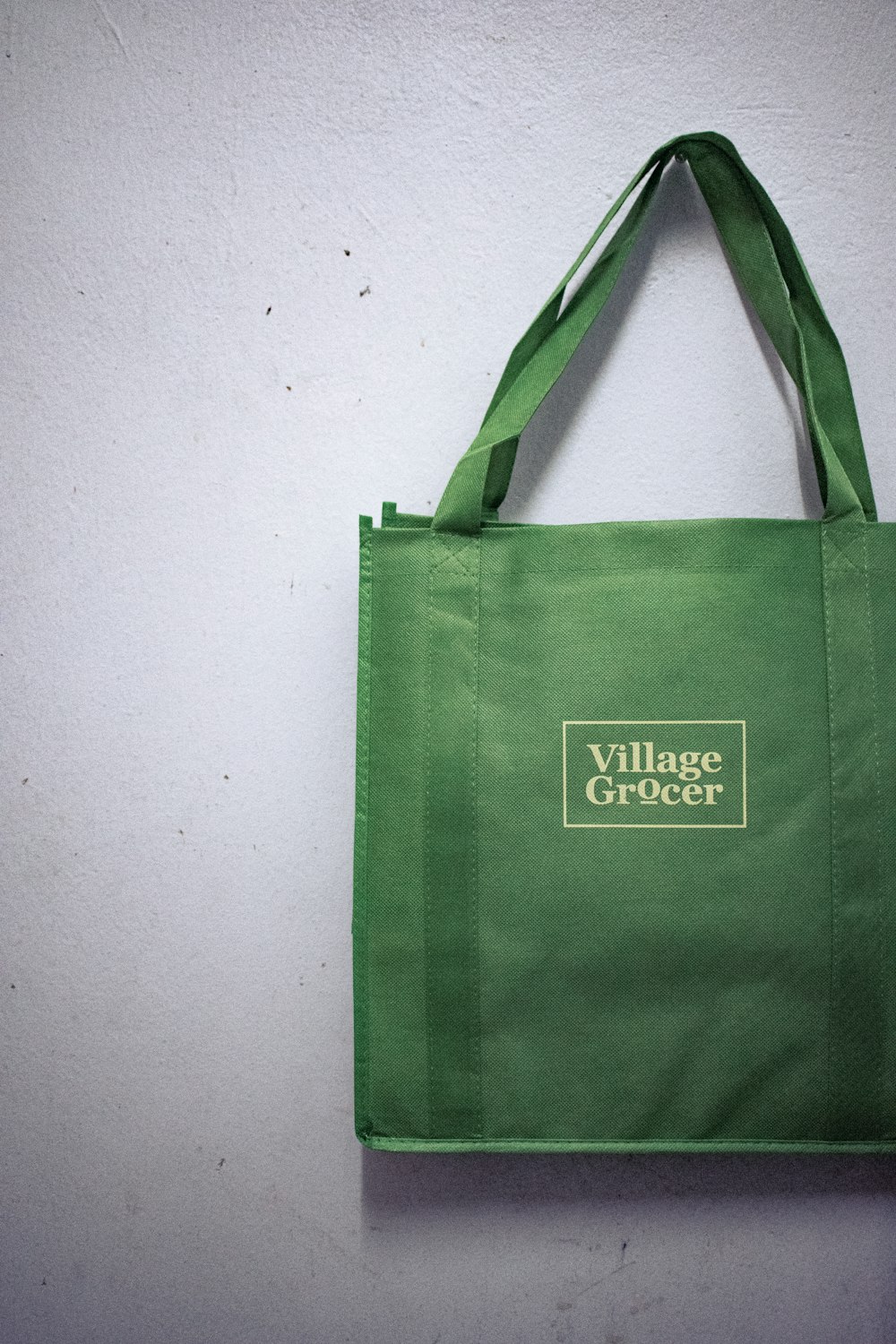 green tote bag on white wall