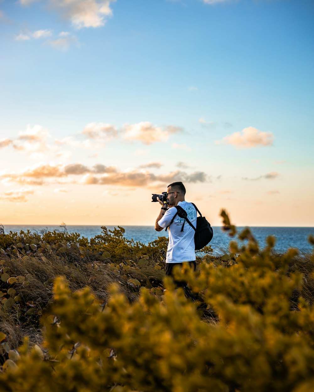 man in blue dress shirt and black pants standing on yellow flower field during daytime