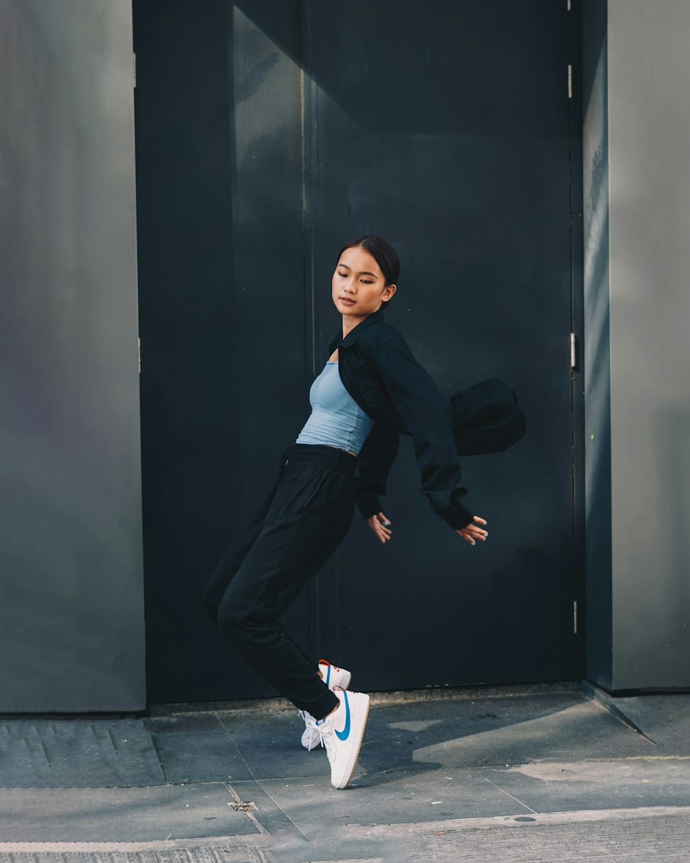 woman in black long sleeve shirt and black pants leaning on black wall