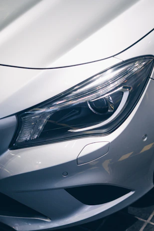 Front bumper of a high-end vehicle gleaming under electric blue accent lighting, protected by clear paint film.