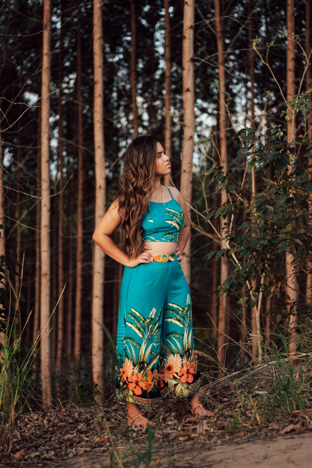 woman in blue and white floral spaghetti strap dress standing in the woods during daytime