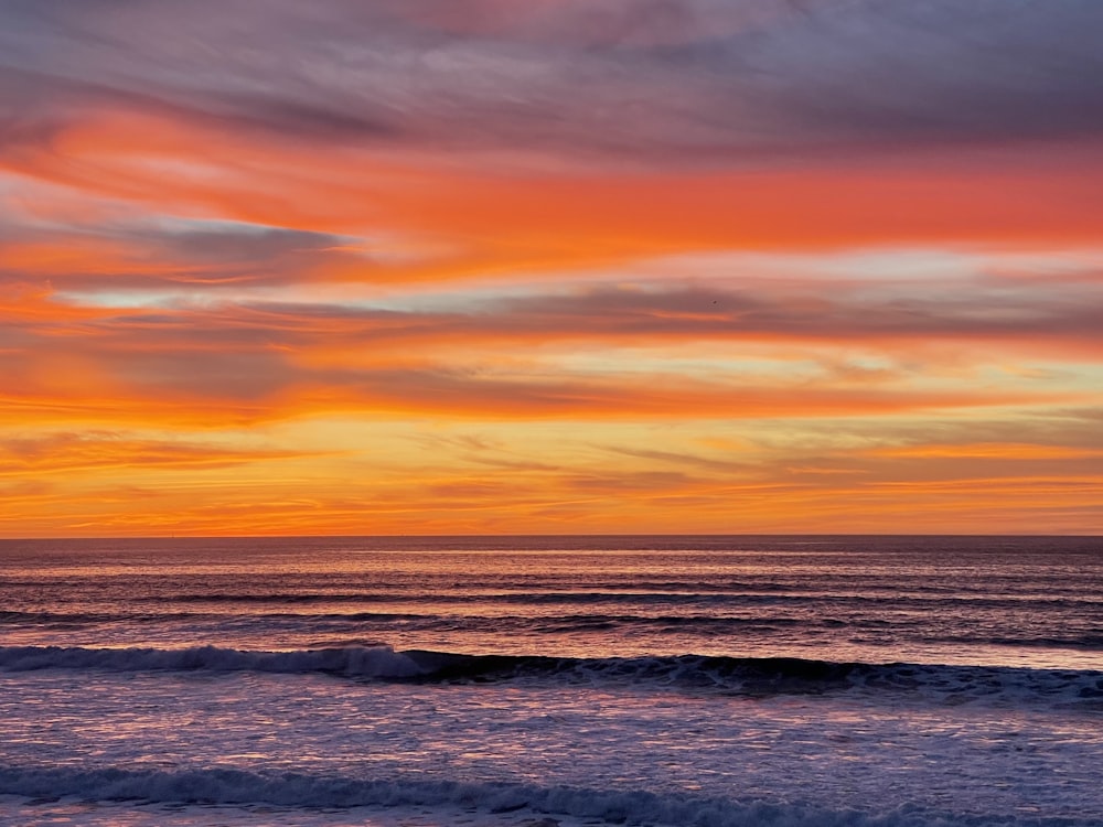 ocean waves under orange and blue sky