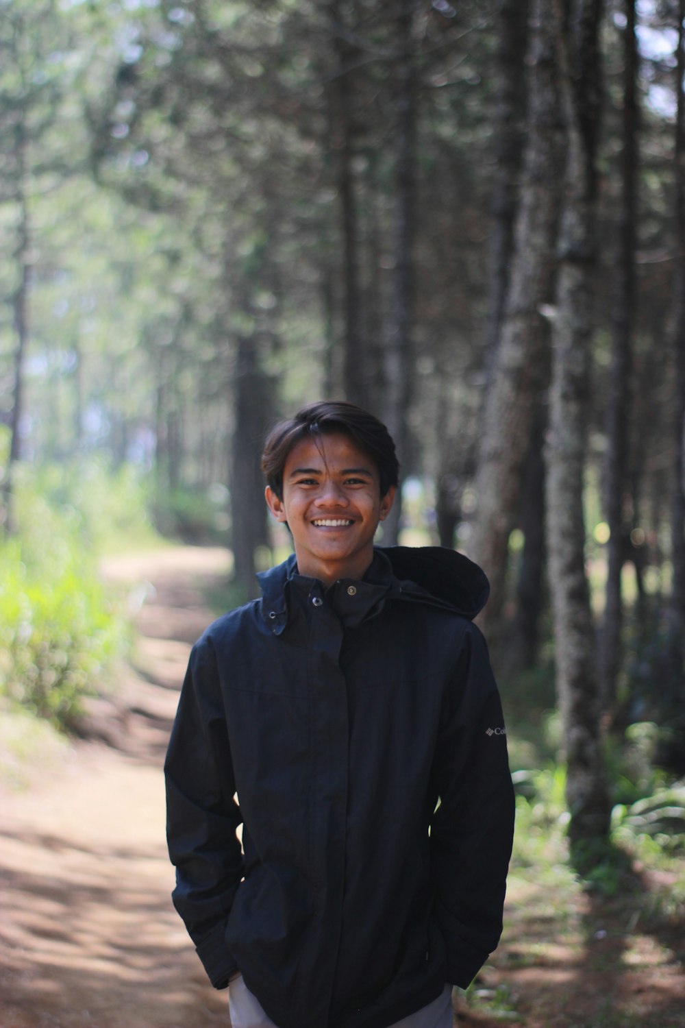 homem na jaqueta preta em pé na floresta durante o dia