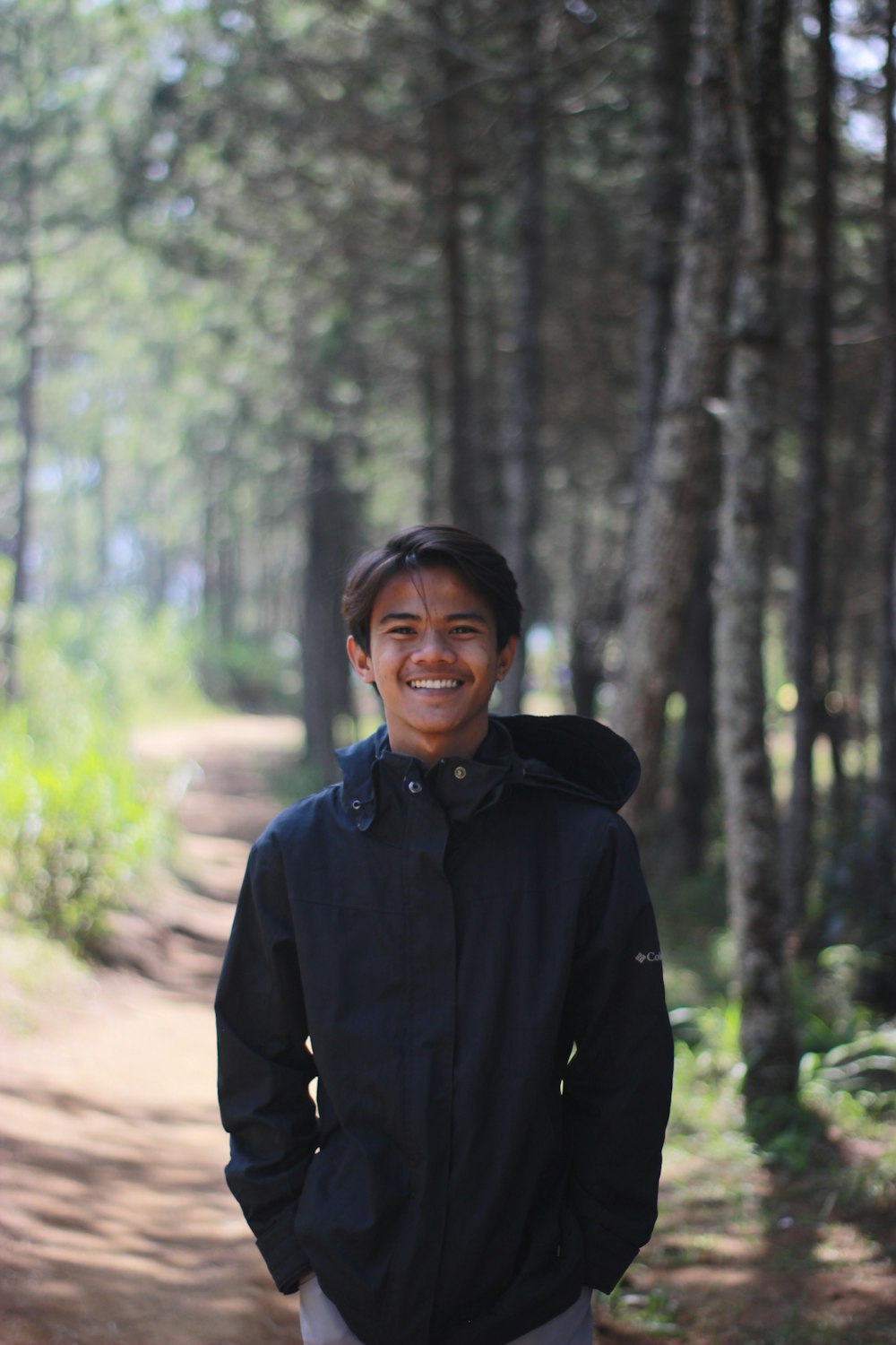 man in black jacket standing in forest during daytime