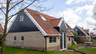 A friendly roofing expert discussing plans with a homeowner in front of a house in Saint-Gilles-Croix-de-Vie.
