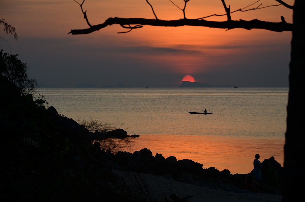 silhouette di persona che cavalca sulla barca sul mare durante il tramonto