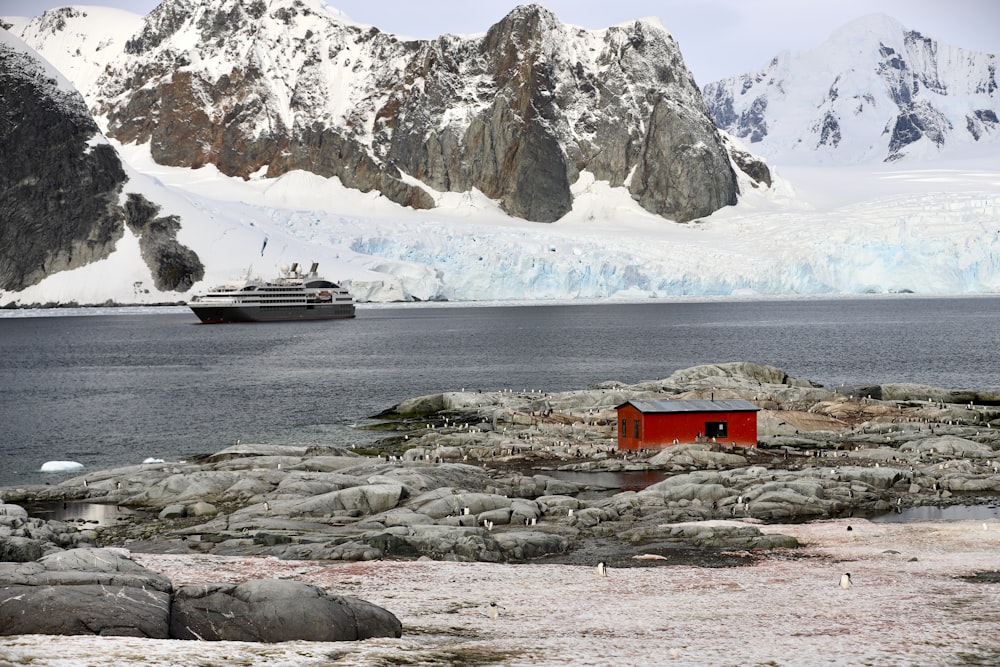 Barco blanco y negro en el mar cerca de la montaña blanca y marrón durante el día