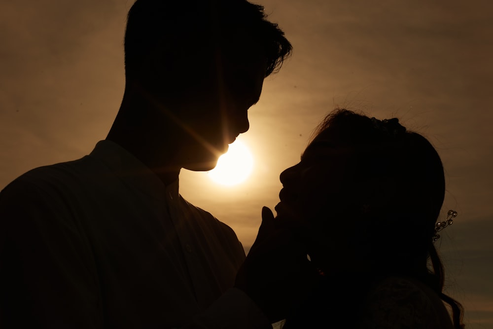 silhouette of man and woman kissing during sunset