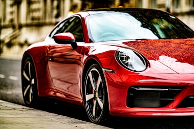 Glossy red hatchback shining on a sunlit city street.