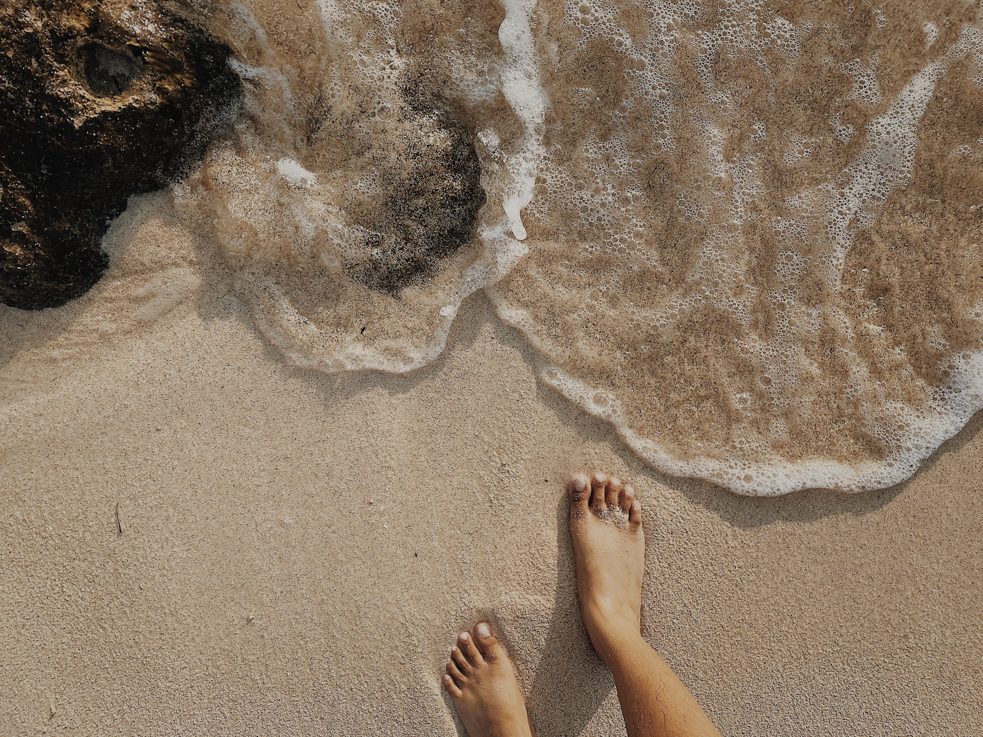 person standing on brown sand near body of water during daytime