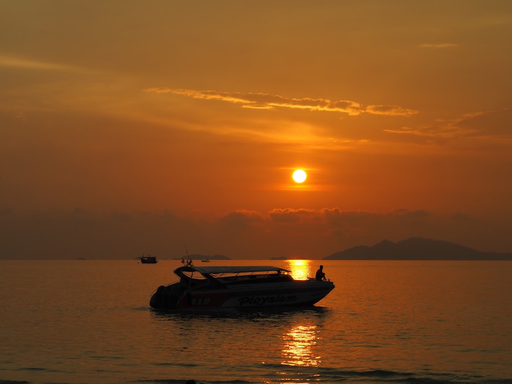 silhouette of boat on sea during sunset