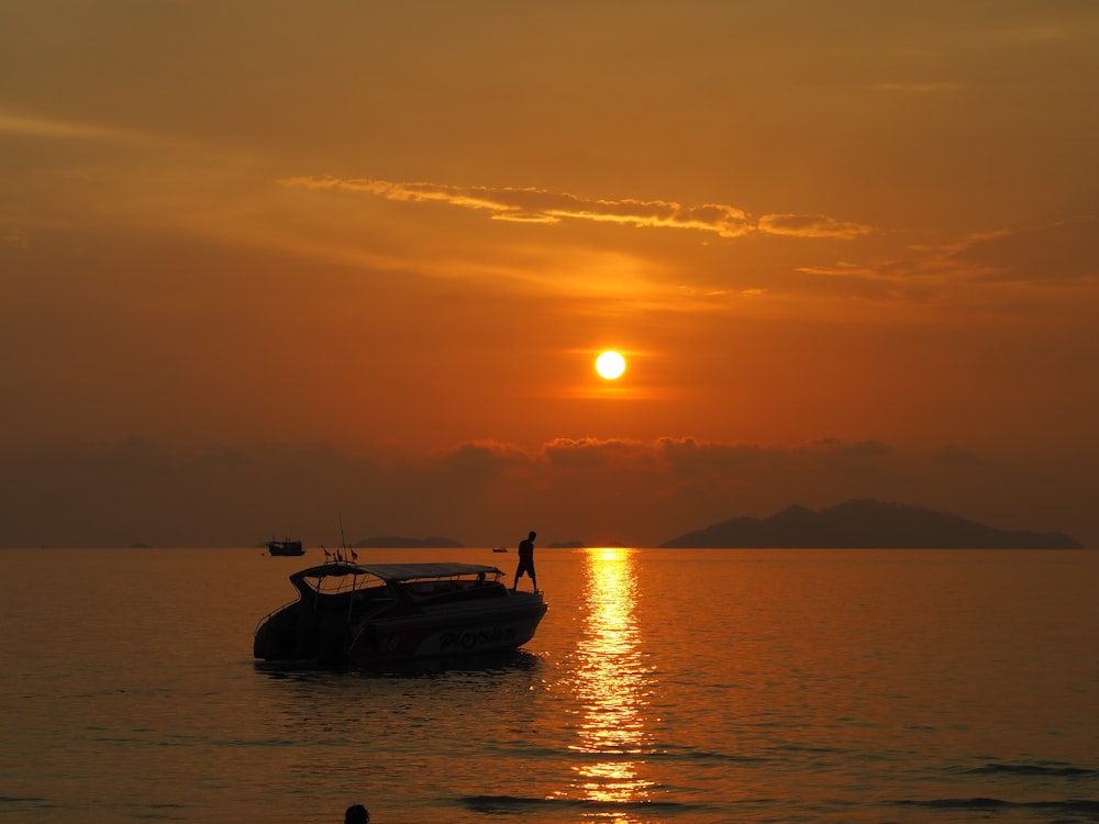 silhouette of boat on sea during sunset