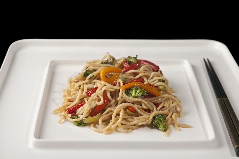 pasta with red sauce and green vegetable on white ceramic plate