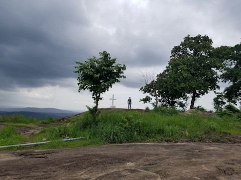 A shadowed figure standing at a crossroads under a stormy sky.